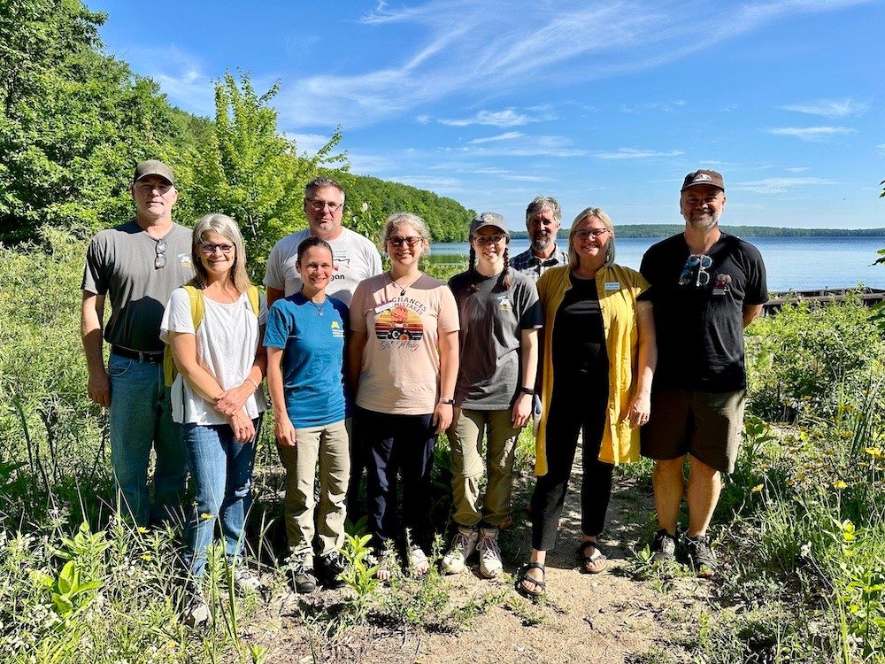 People posed for a group photo along a lake