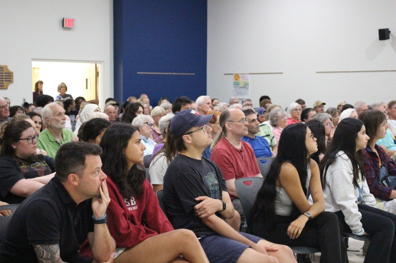 People in a crowd in a lecture hall listening to the speaker