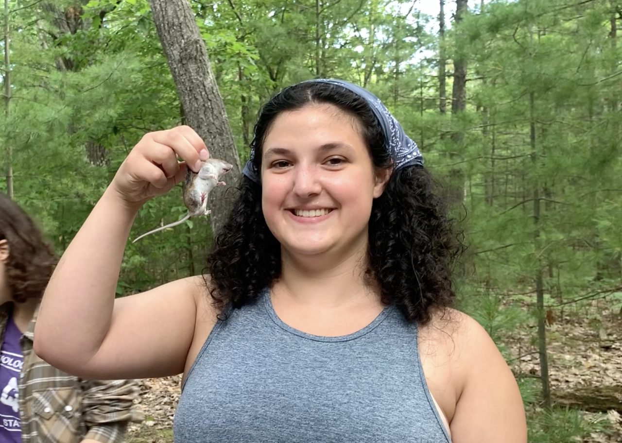 Woman holds mouse in a forest
