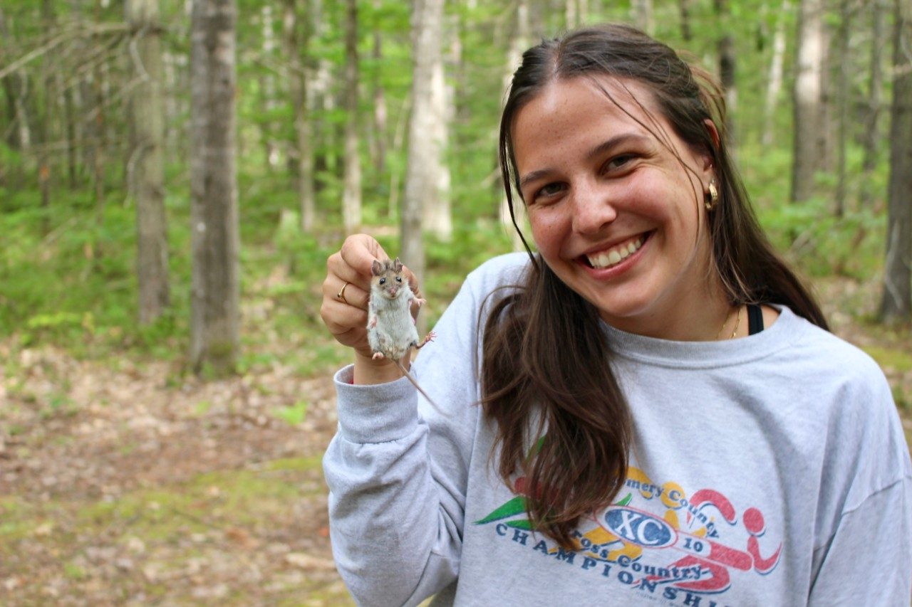 Woman holding a mouse in a forest