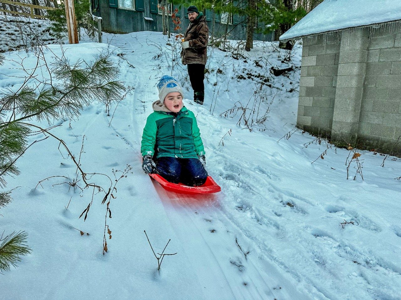 Boy sledding down hill in the snow