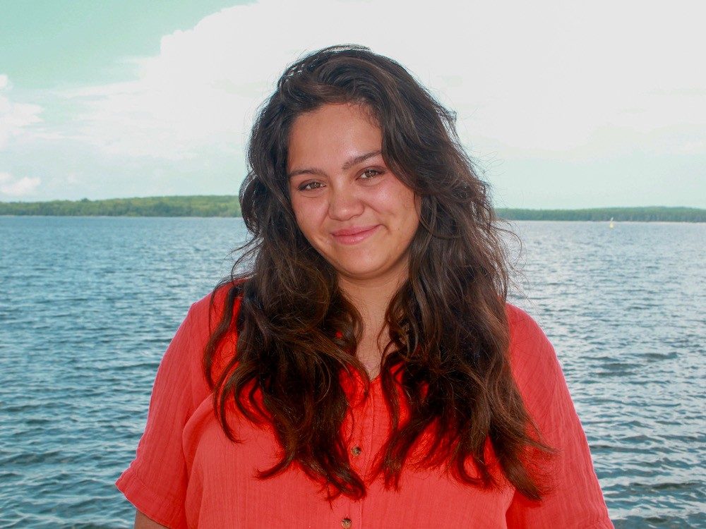 Woman smiling at camera in front of lake