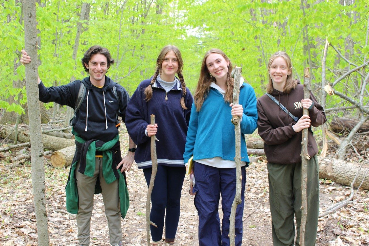 People posing together holding walking sticks in a forest