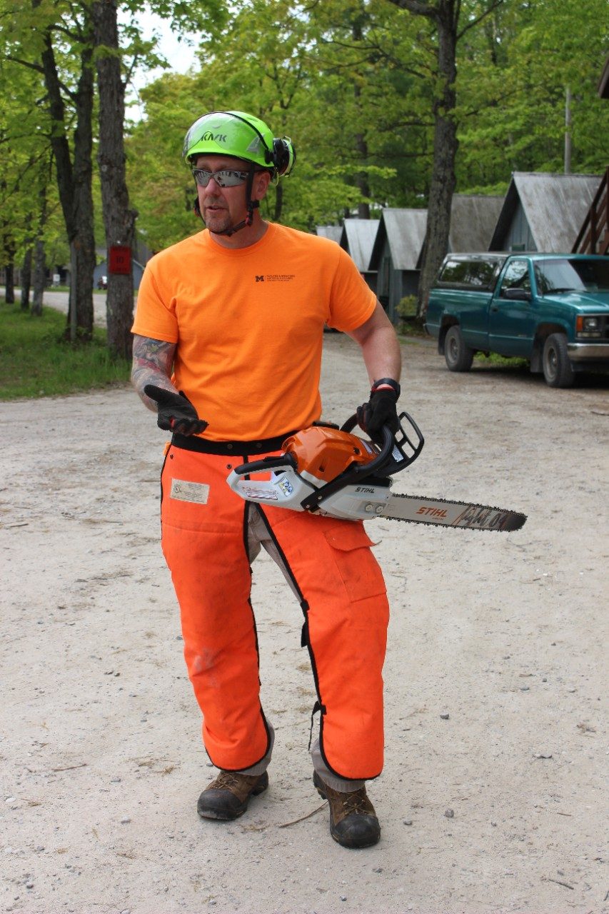 Man wearing safety gear and holding a chainsaw
