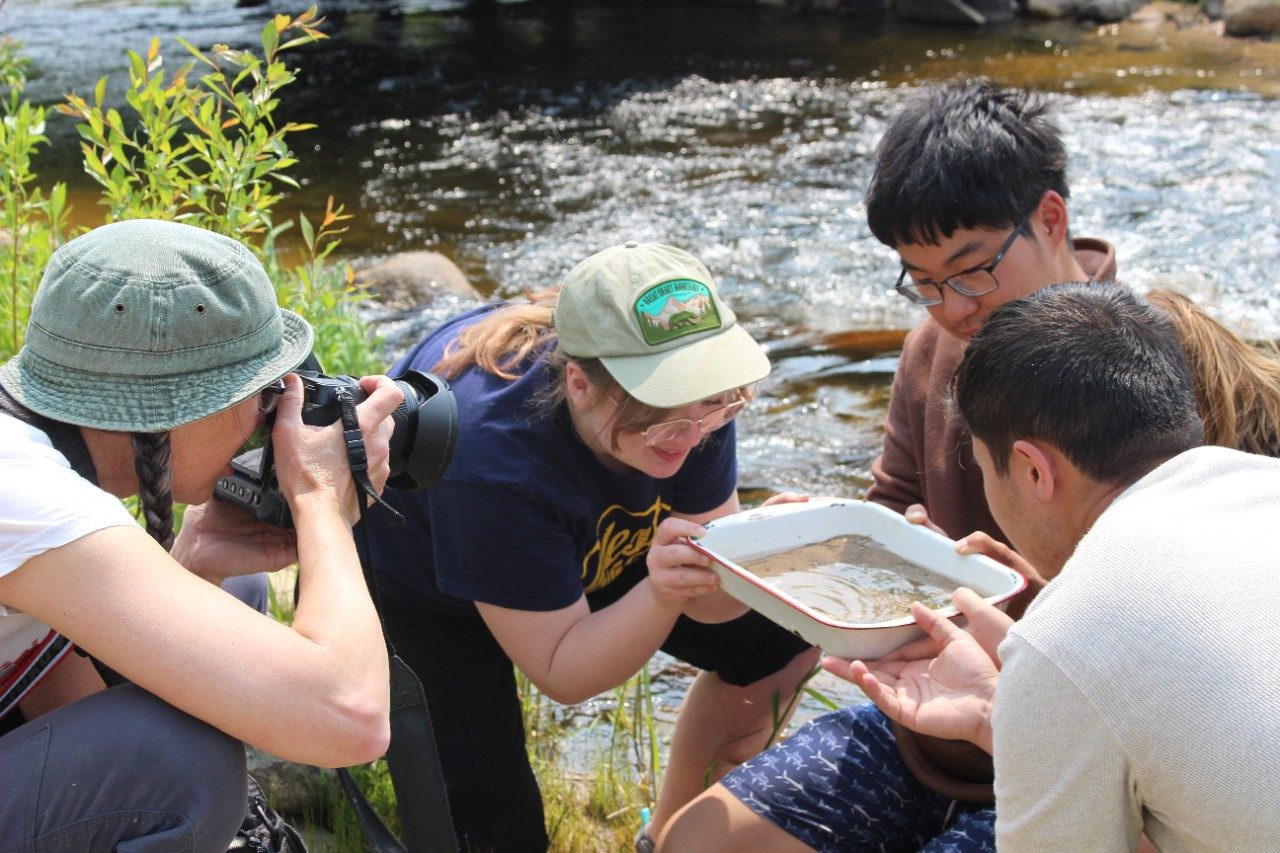 Person taking a picture of students along a river