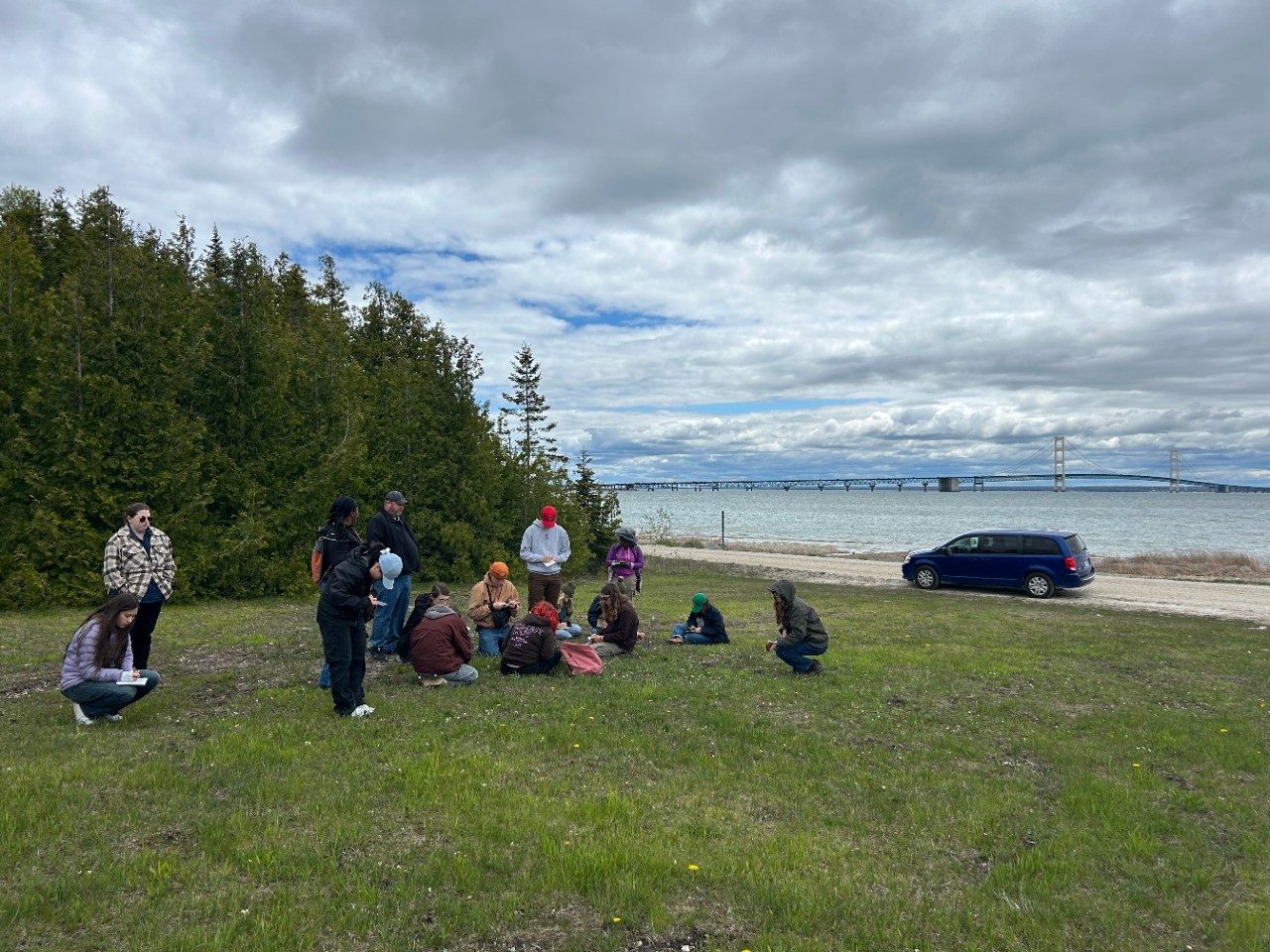 People in grass along a lake