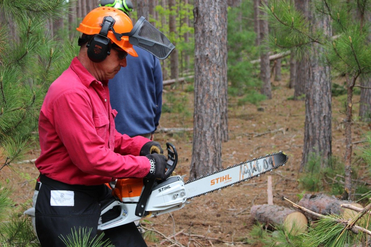 Man wearing safety gear and holding a chainsaw