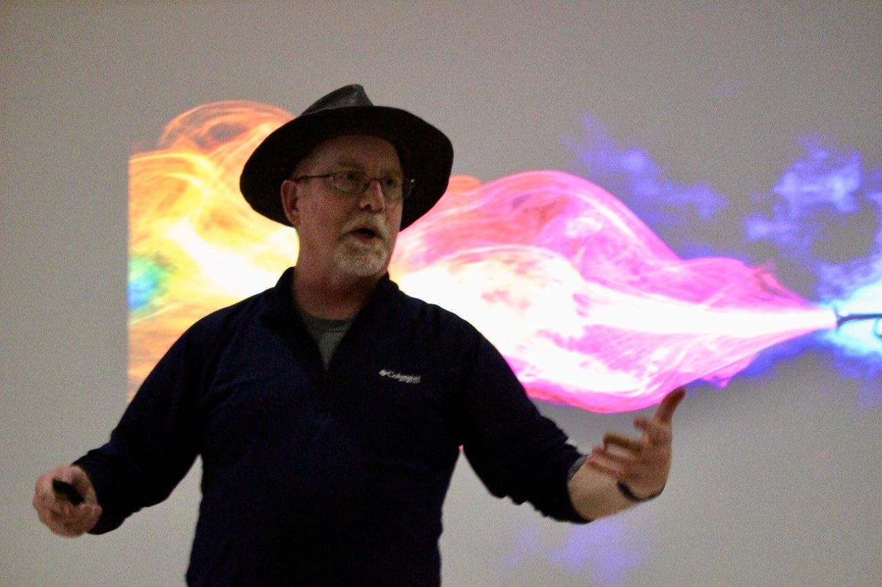 Man talking in front of a screen with colors on it