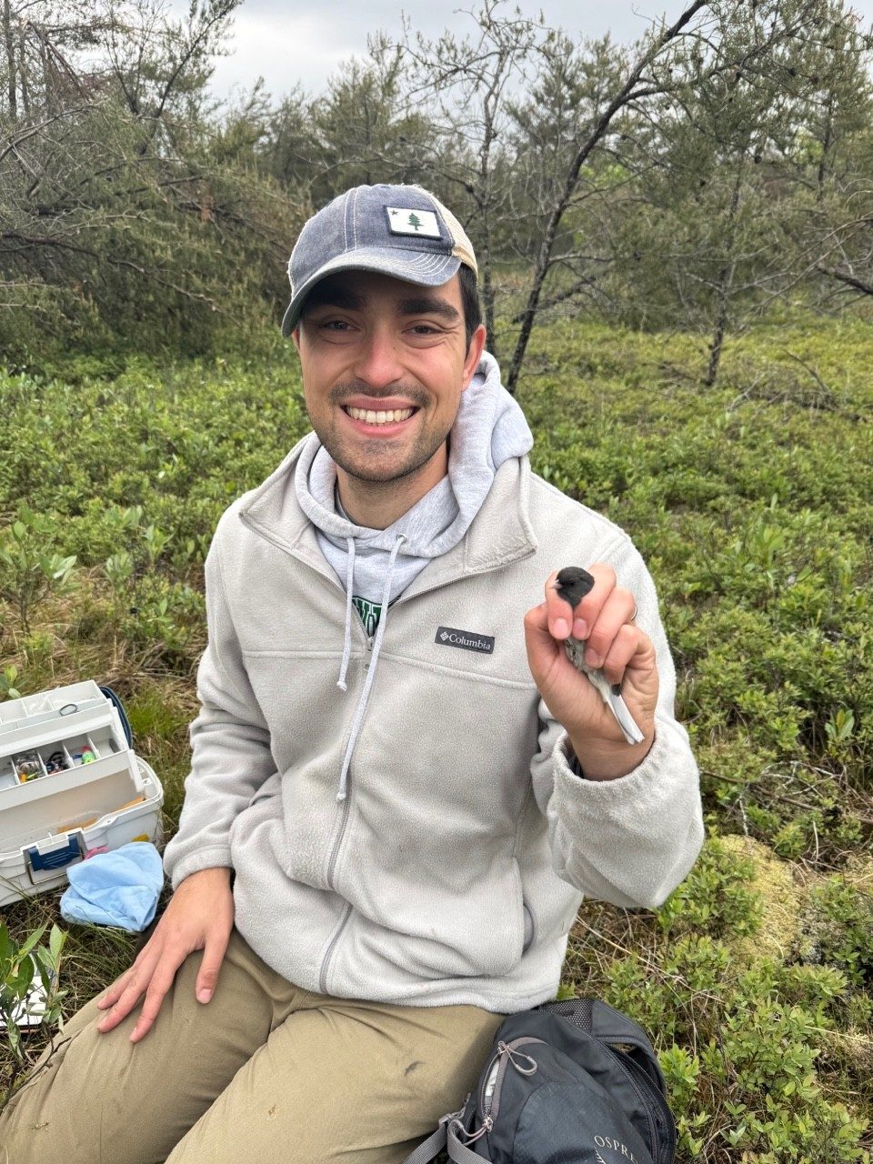 Man holding a bird in a forest