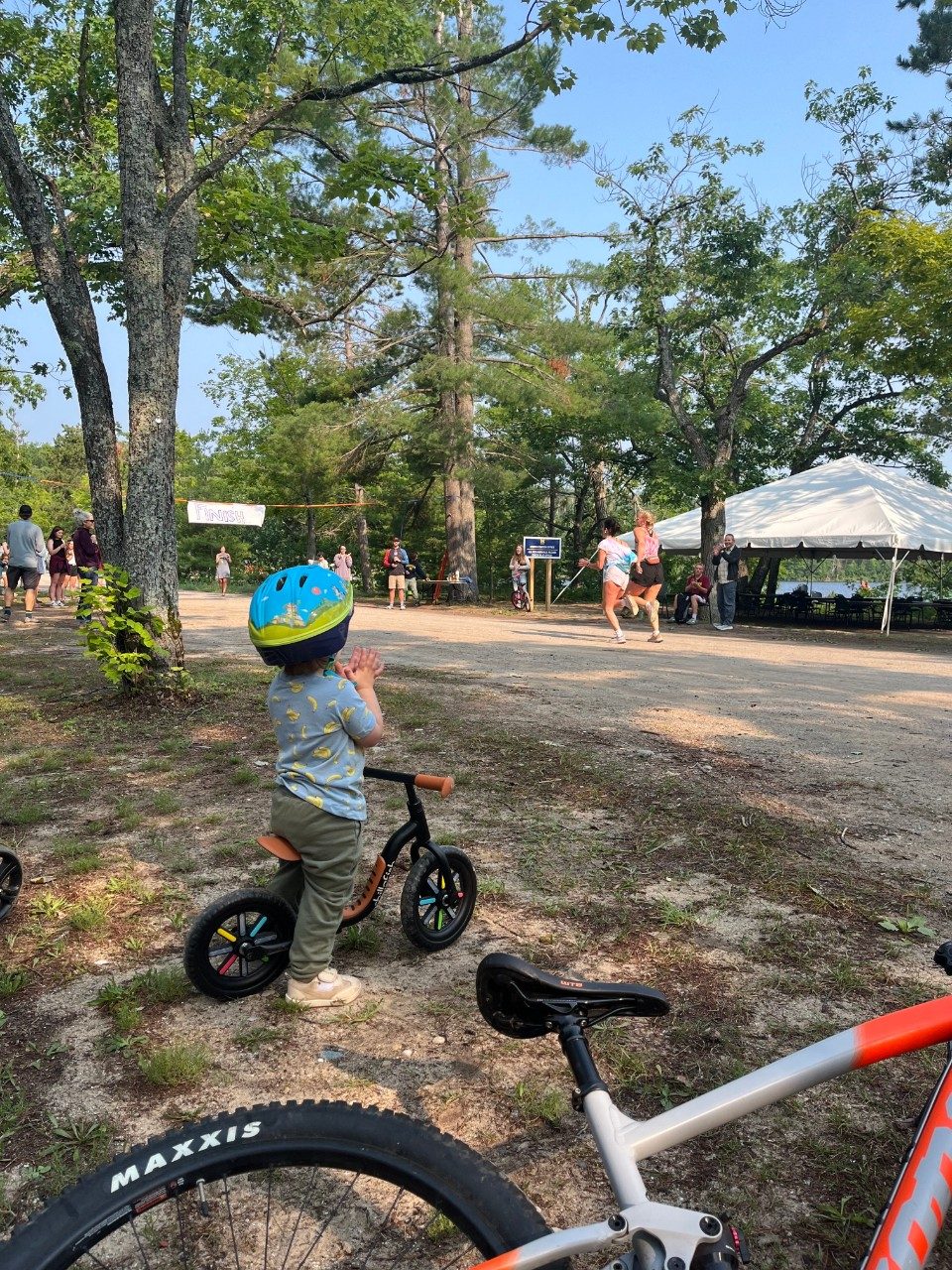 Child on a bike, standing and cheering on the sidelines for runners during a race