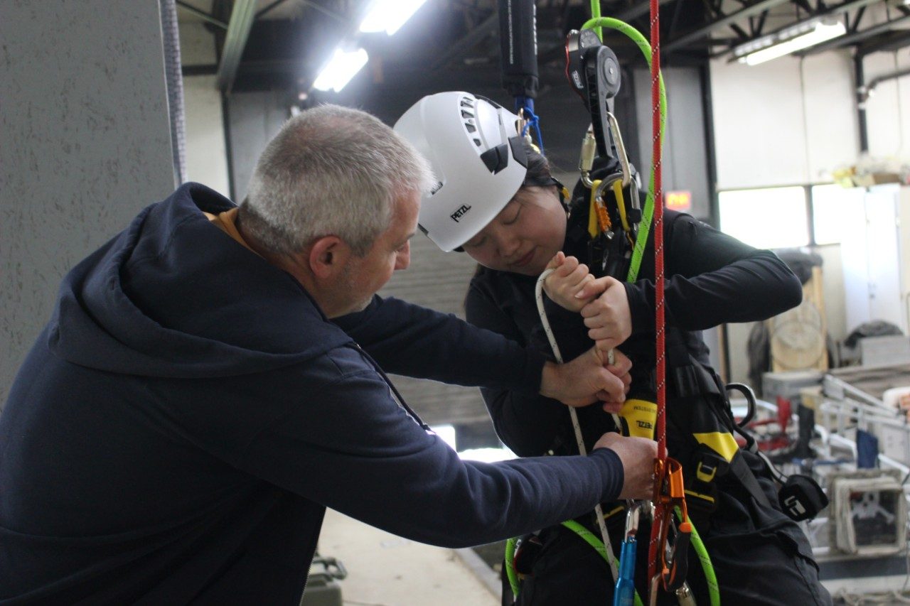 Person helping another person into a roped harness