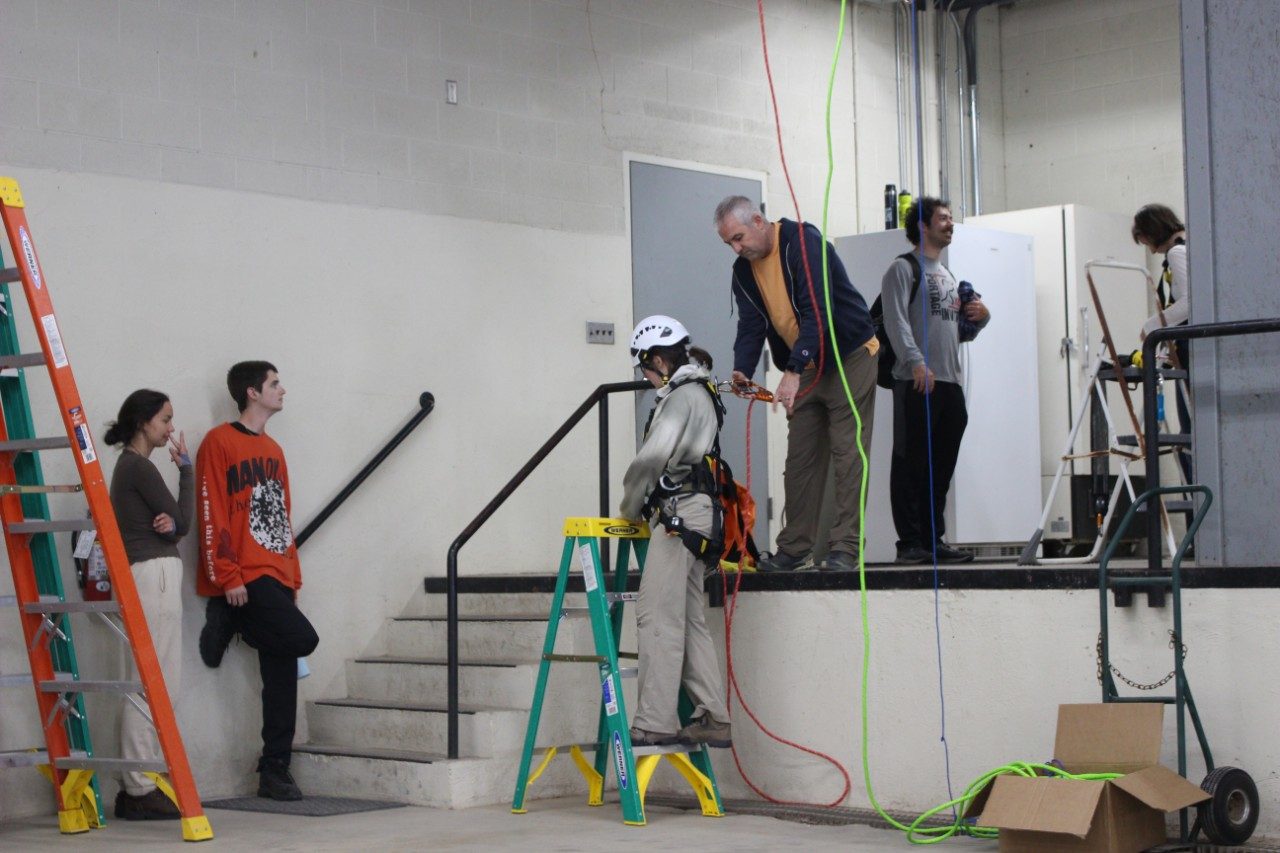 People in a room getting strapped into harnesses