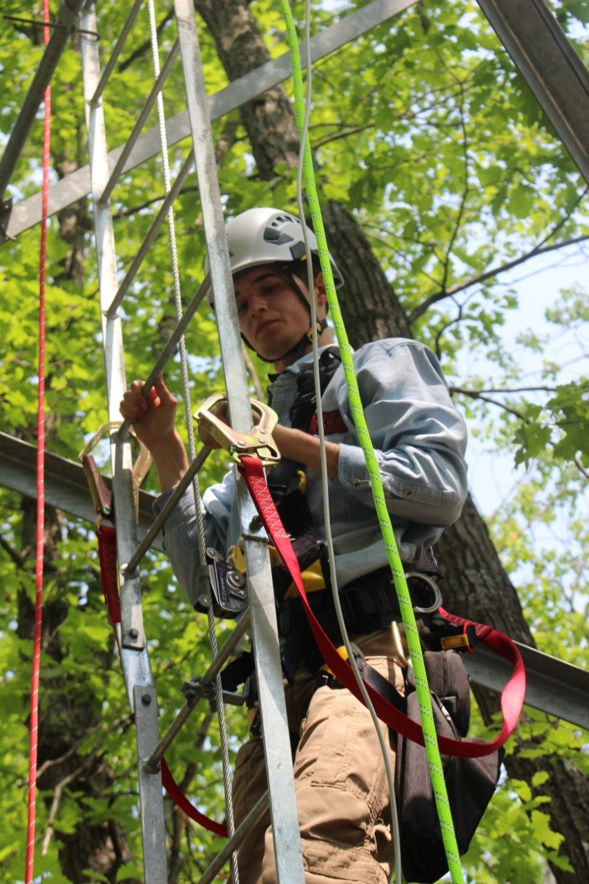 Person climbing a tower while wearing a harness