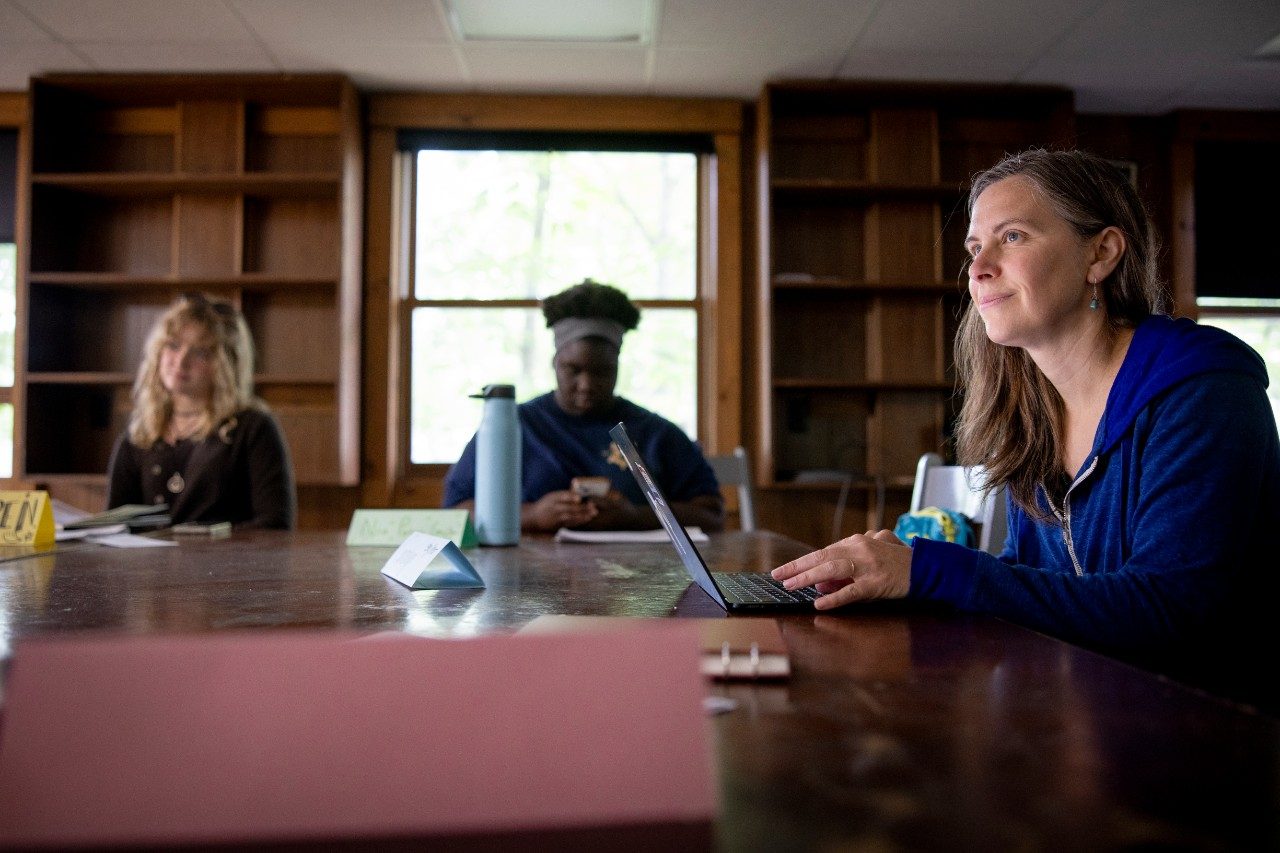 Woman sitting at a table in a classroom teaching students