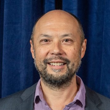 Head shot photo of a man in front of a theater curtain
