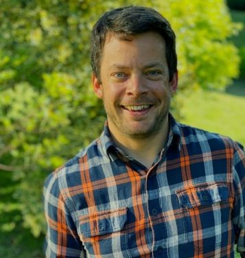 Headshot photo of a man in front of trees