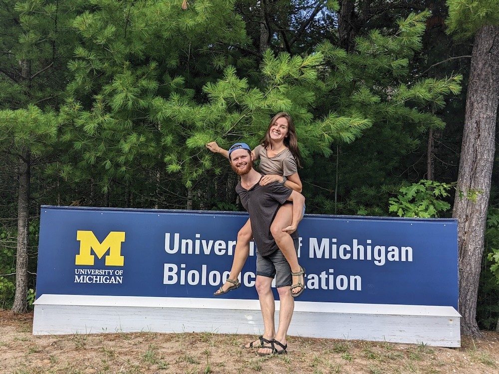 Two people standing next to a sign