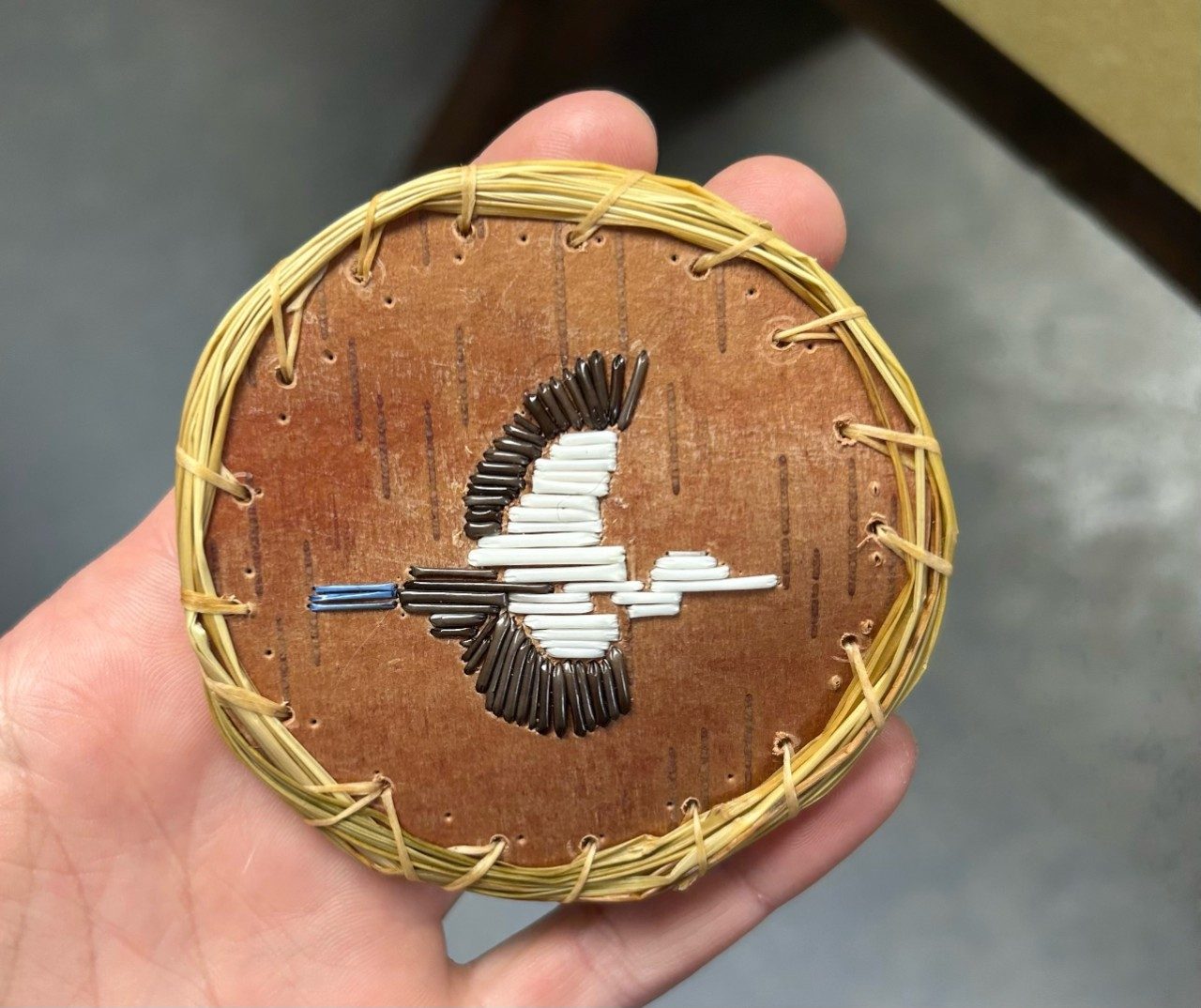 A birchbark medallion that was sewed with sweetgrass