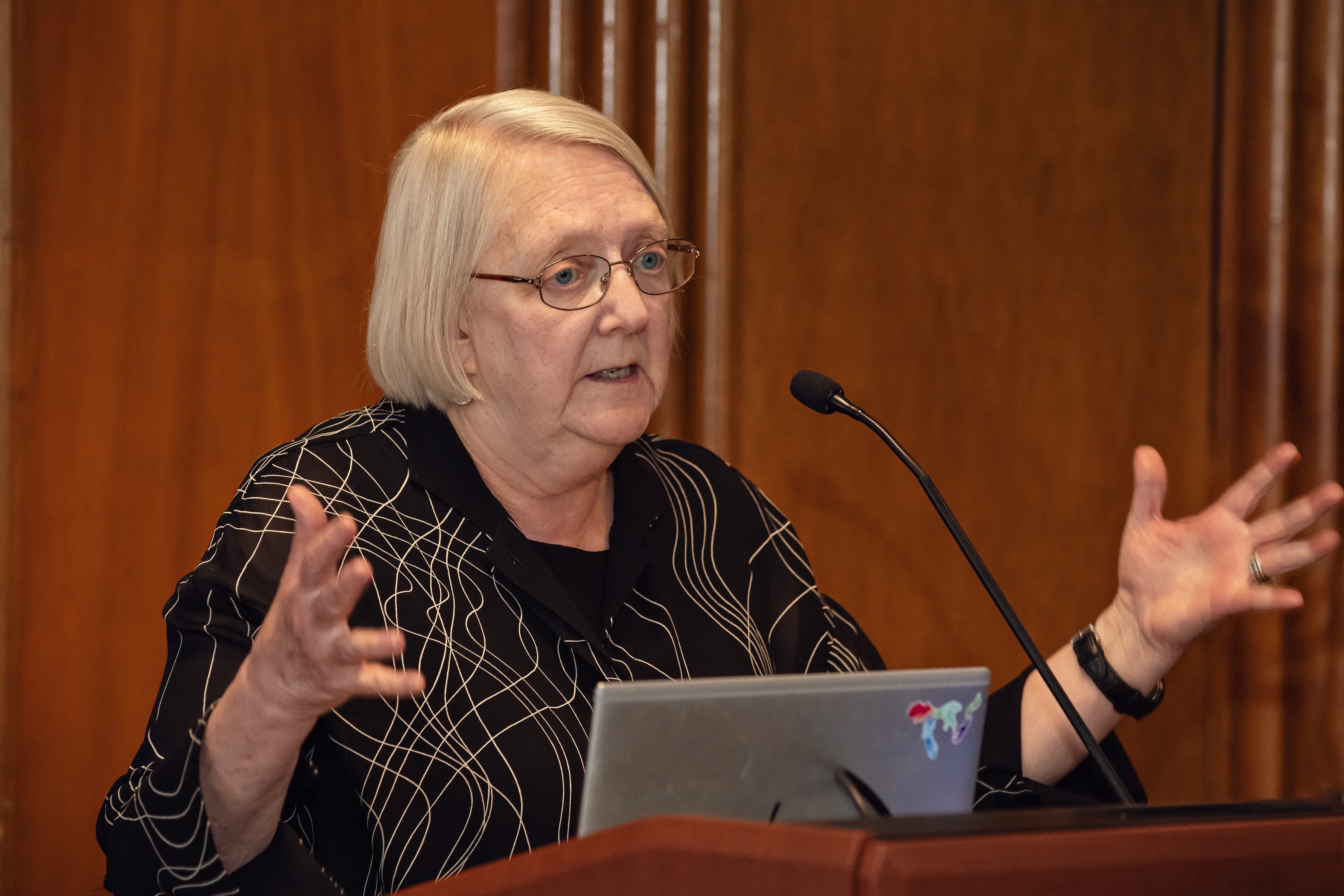 Abby Stewart in a black outfit speaking at a podium