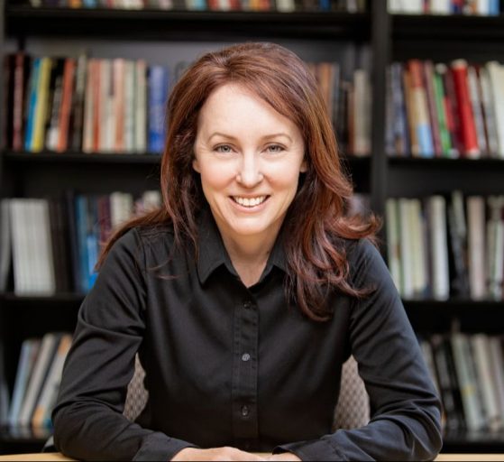 Prof. kirkland smiles in a black shirt against a multi-color background