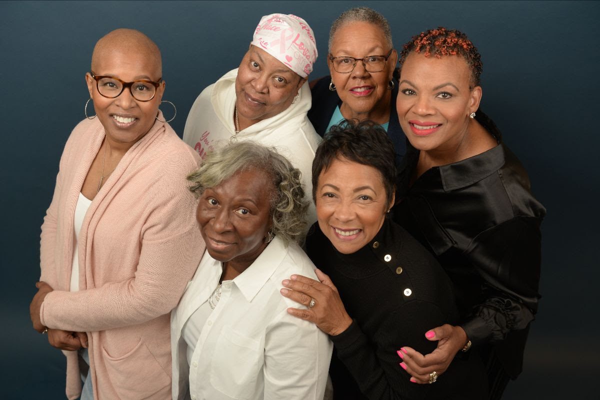Six black women face the camera smiling on a neutral background.