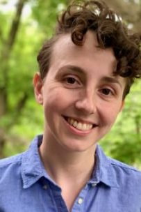 Emily Coccia smiling in a blue shirt against a green background