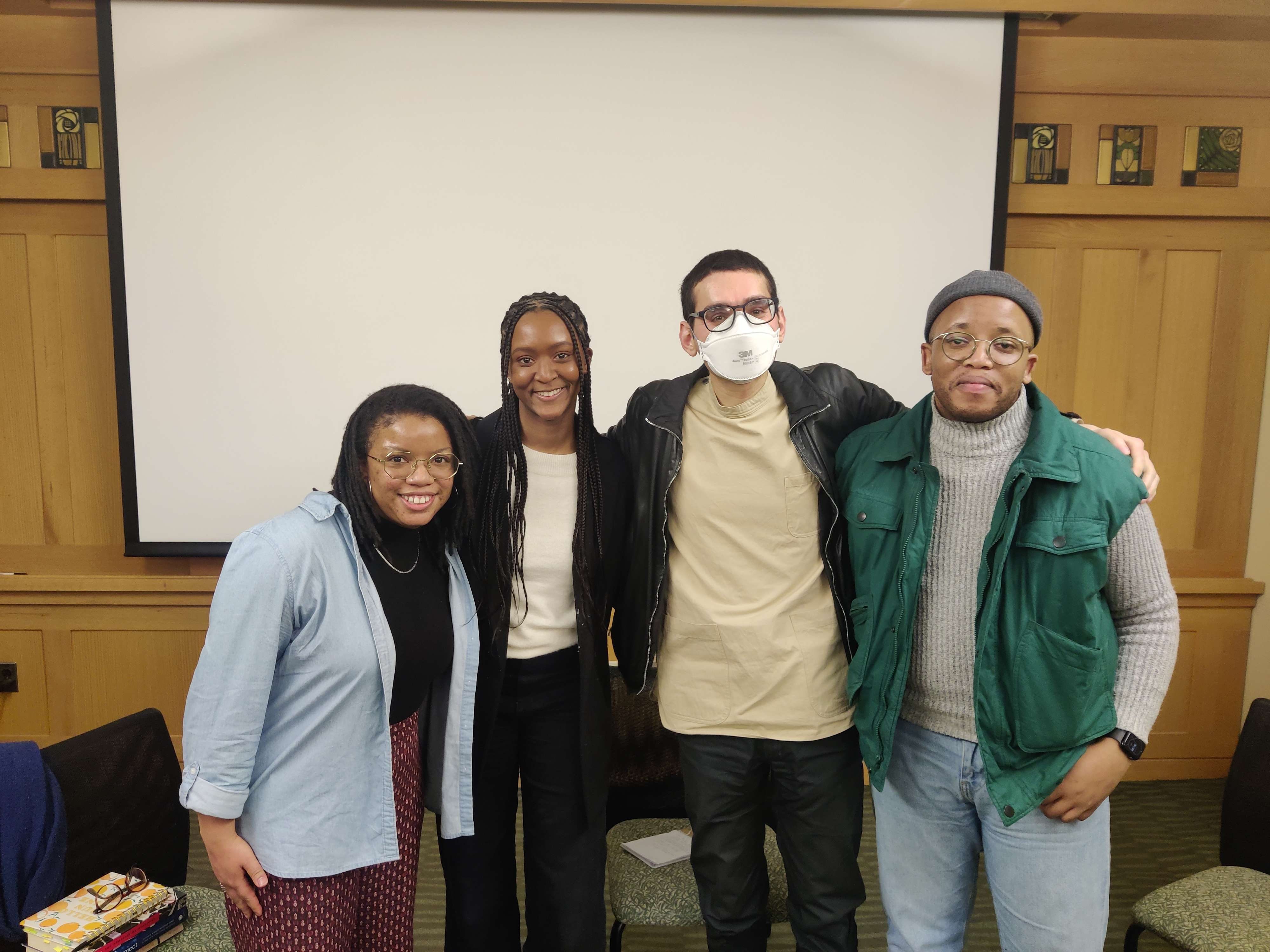 Four people smiling against a neutral background