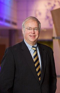 Dr. Johnson smiling in a suit against a multicolored background