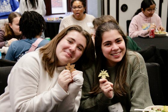 two students holding up paper leaves